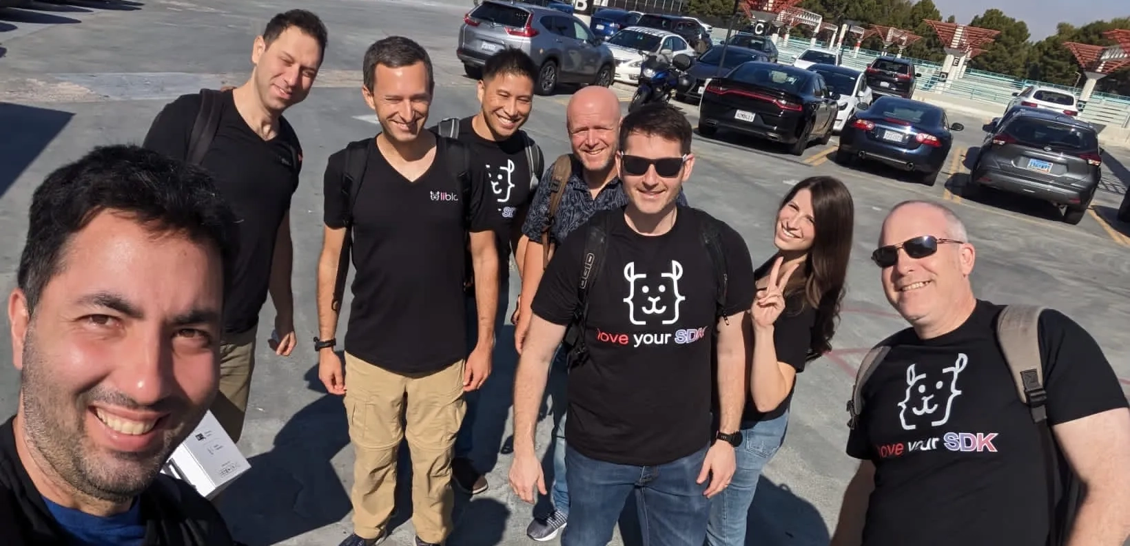A group of people posing for a selfie wearing liblab shirts standing in a carpark. 2 of the team are wearing sunglasses, and another is making a peace sign